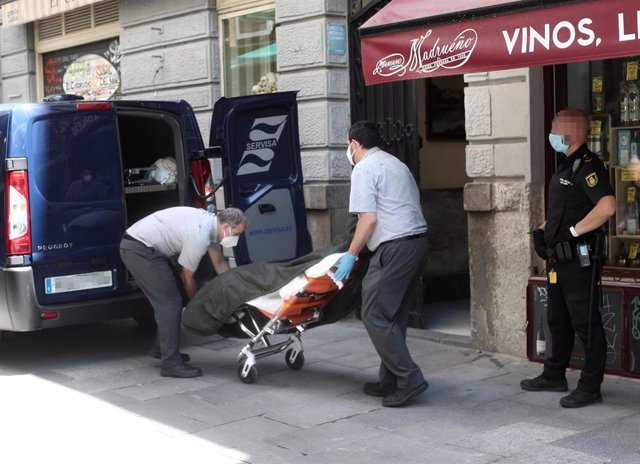 Dos trabajadores de la Funeraria Servisa recogen los cuerpos sin vida del hostal de la calle Postigo de San Martín de Madrid, donde la Policía Nacional halló los cadáveres de una mujer de 36 años y su hijo de 6 años