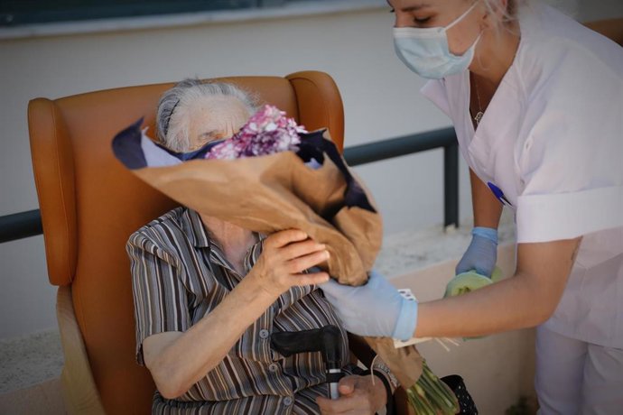 Una residente de la Residencia de Mayores Pablo Neruda recibe un ramo de flores durante el "Día de los Mayores", una celebración convocada por la Asociación de Víctimas del COVID-19. En Ciempozuelos, Madrid (España) a 28 de junio de 2020 (archivo)