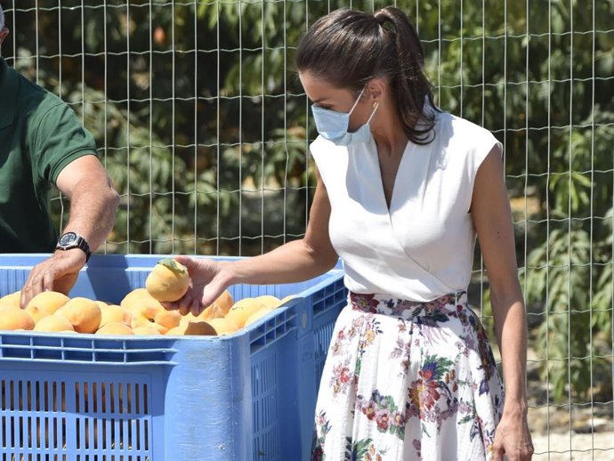 La Reina Letizia coge un melocotón durante su visita a la cooperativa de frutas La Carrichosa, en Cieza