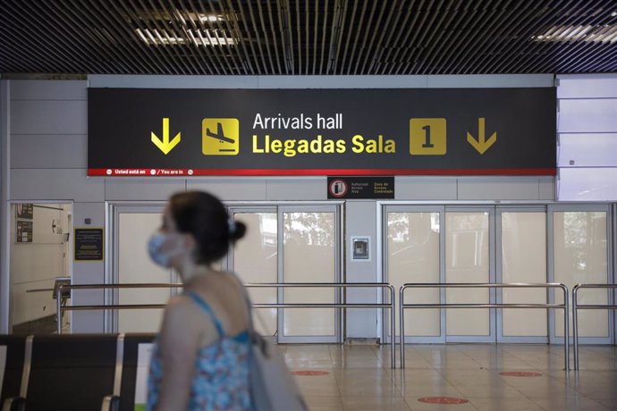 Una persona con mascarilla pasa junto a la entrada de la sala de llegadas 1 de la Terminal 1 del Aeropuerto de Barajas, en Madrid (España) a 4 de julio de 2020. 