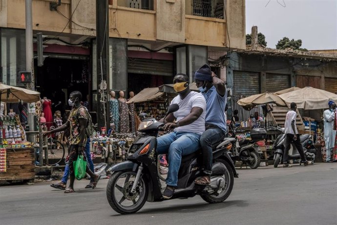 Dos hombres con mascarilla en una moto en Dakar