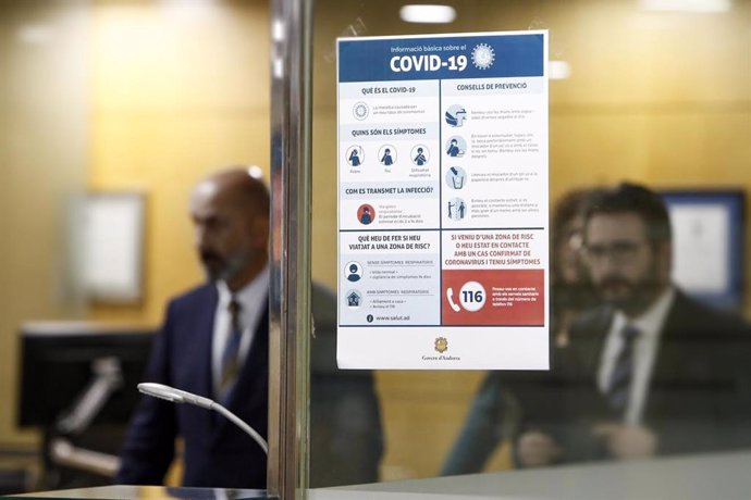 Los ministros de Salud, Joan Martínez Benazet, y Portavoz, Eric Jover, detrás de un cartel informativo sobre el Covid-19