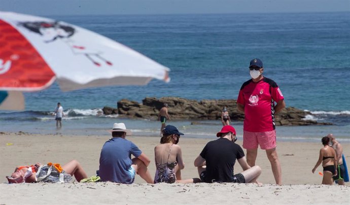 Varias personas protegidas con mascarillas toman el sol en la Playa de A Rapadoira en Foz, en la comarca de A Mariña, Lugo, Galicia (España), a 9 de julio de 2020. 