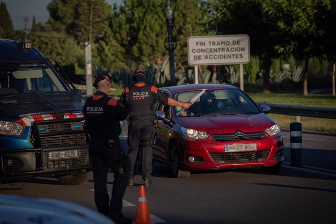 Un Mosso d'Esquadra controla el acceso a la A2 dirección Barcelona en Lleida, capital de la comarca del Segri, en Lleida, confinada por un brote de Covid-19