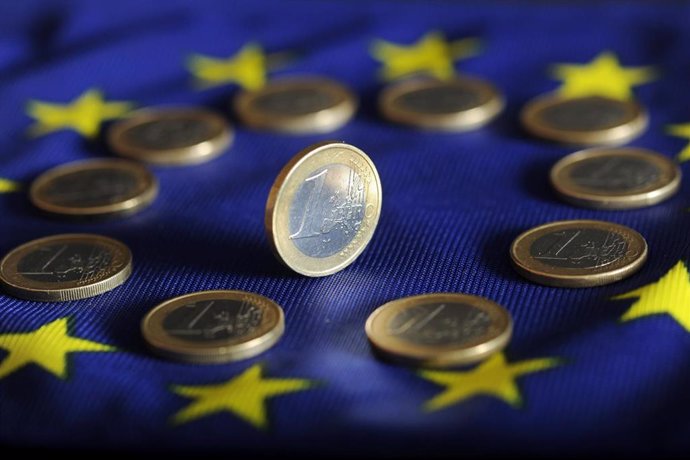 Monedas de euro sobre una bandera de la UE