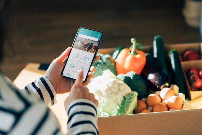 Un mujer comprando verduras frescas 'online' con su smartphone a través de una aplicación