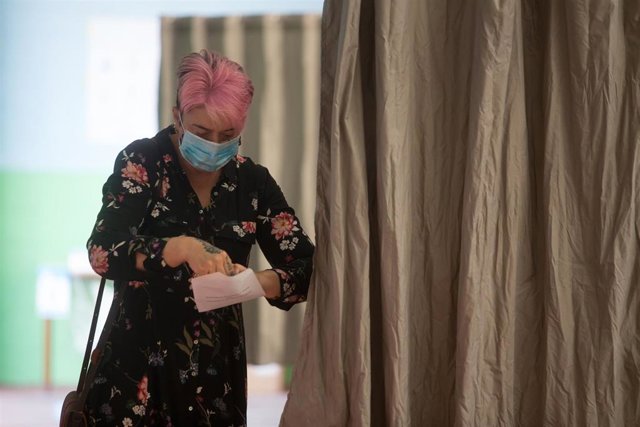 Una mujer introduce su voto en un sobre en las elecciones autonómicas de Galicia en la población de Burela.