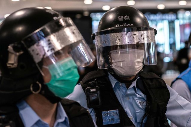 Imagen de dos policías con protección y mascarilla por el coronavirus en Hong Kong. 