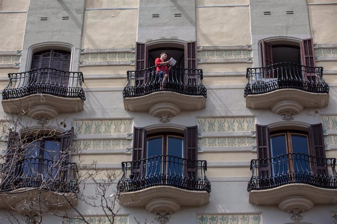 Un joven lee un libro en el balcón de su casa con ocasión de la Diada de Sant Jordi, en la que es costumbre regalar libros y rosas, en Barcelona / Catalunya (España), a 23 de abril de 2020 (archivo)