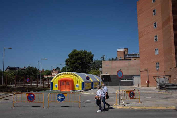 Dos personas pasan cerca del Hospital de campaña para atender a enfermos de coronavirus junto al Hospital Universitario Arnau de Vilanova de Lleida, capital de la comarca del Segri, en Lleida, Catalunya (España), a 6 de julio de 2020. El presidente de 