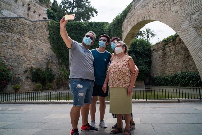 Varios turistas se hacen una foto junto a los Jardines de S'Hort del Rei de Palma de Mallorca durante el primer día de uso obligatorio de la mascarilla en Baleares por el Covid-19, en Palma de Mallorca, Islas Baleares (España) a 13 de julio de 2020. 