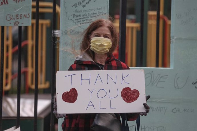 Una mujer portando un cartel con el mensaje "Gracias a todos"