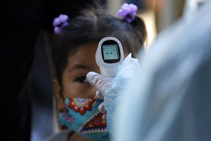 Niña boliviana se somete a un control de temperatura en Santiago de Chile durante la pandemia de coronavirus