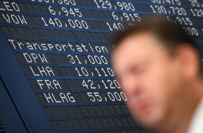 22 June 2020, Hessen, Frankfurt/Main: A stock market expert stands on the floor of the Frankfurt Stock Exchange during an interview in front of the scoreboard on which the Lufthansa (LHA) share can be seen. Photo: Arne Dedert/dpa