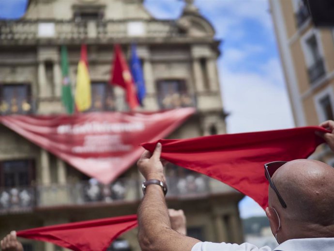 Un hombre alza un pañuelo rojo en las inmediaciones de la Plaza del Consistorio en el momento en el que de celebrarse los Sanfermines 2020 hubiera tenido lugar el famoso chupinazo