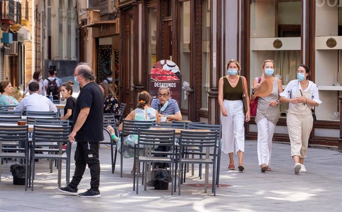 Tres ciudadanas pasean con mascarillas y abanico por el fuerte calor  en el primer día  de uso obligatorio de mascarillas en Sevilla a 15 de julio del 2020
