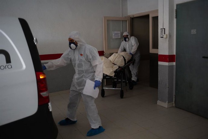 Varios operarios protegidos de los Servicios Funerarios Memora trasladan un cuerpo de una residencia  en el garaje de una residencia de ancianos 