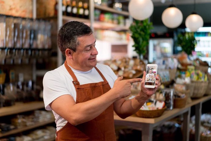 El dueño de una pyme de alimentación muestra en su smartphone un sistema para vender online sus productos