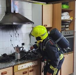 Un bombero comprueba la campana extractora afectada por las llamas.