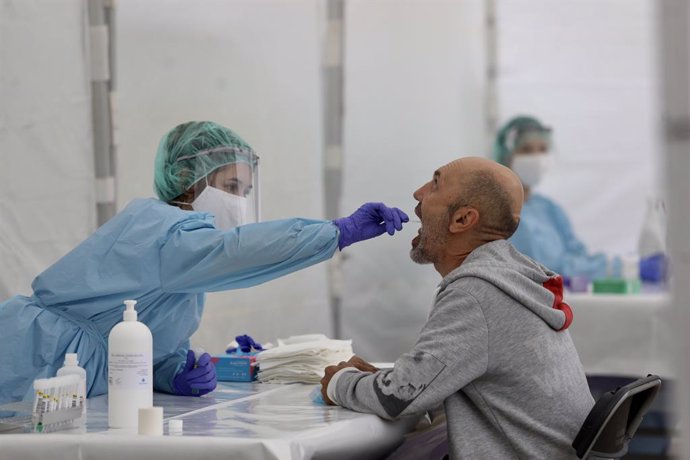 Una sanitria fa un frotis bucal a una persona per fer una PCR (Arxiu)