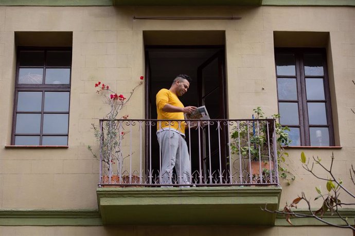 Un hombre lee un libro en el balcón de su casa con ocasión de la Diada de Sant Jordi de 2020 marcada por el coronavirus (Archivo)