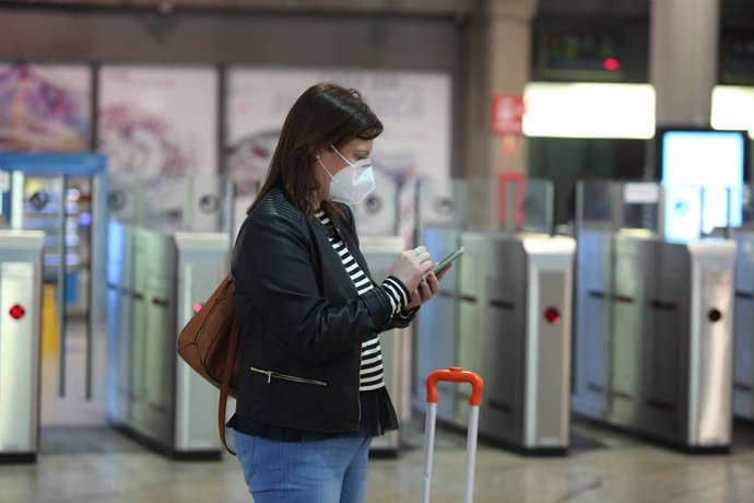 Una viatgera amb mascarilla consulta el seu mbil en l'estació d'Atocha, a Madrid (Espanya), a 14 de maig de 2020.