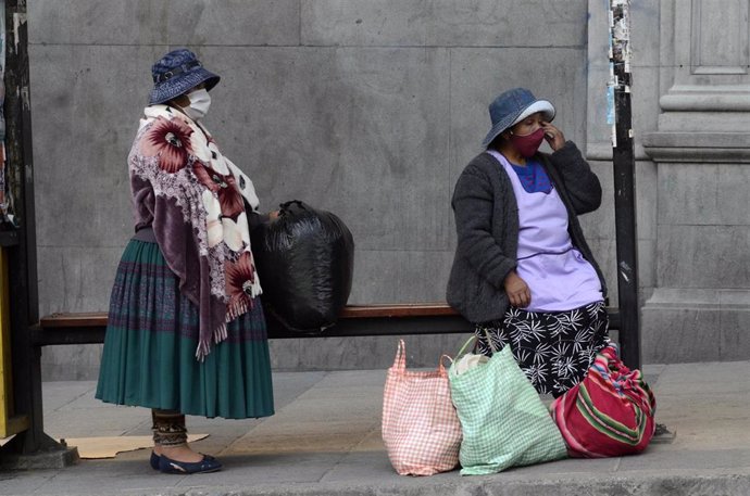 01 June 2020, Bolivia, La Paz: Two women with face masks wait for the bus at a bus stop amid the relaxations of restrictions that were put into effect to curb the spreading of coronavirus. Photo: Alexis-Demarco/ABI/dpa