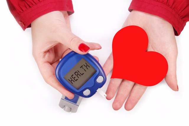 Two female hands holding a blood testing machine and heart