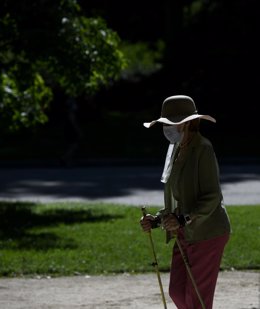 Una mujer camina con bastones en el Parque del Retiro en Madrid (España), a 29 de junio de 2020. El calor pone desde este lunes en aviso a una quincena de provincias de Andalucía, Castilla y León, Castilla-La Mancha, Extremadura y Madrid, por temperatur