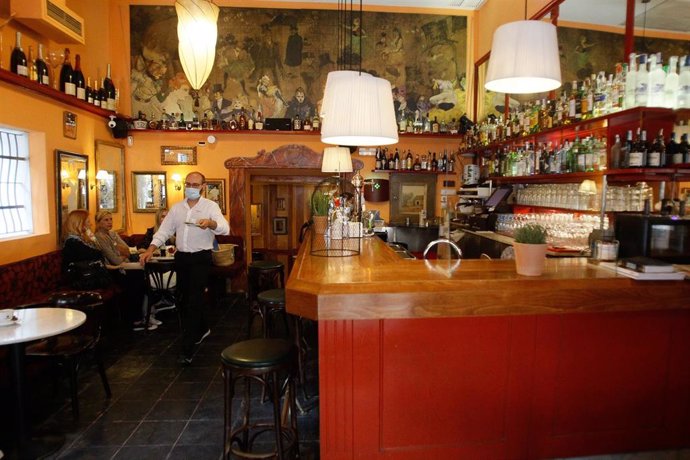 Una camarero sirve una mesa en el interior de un bar