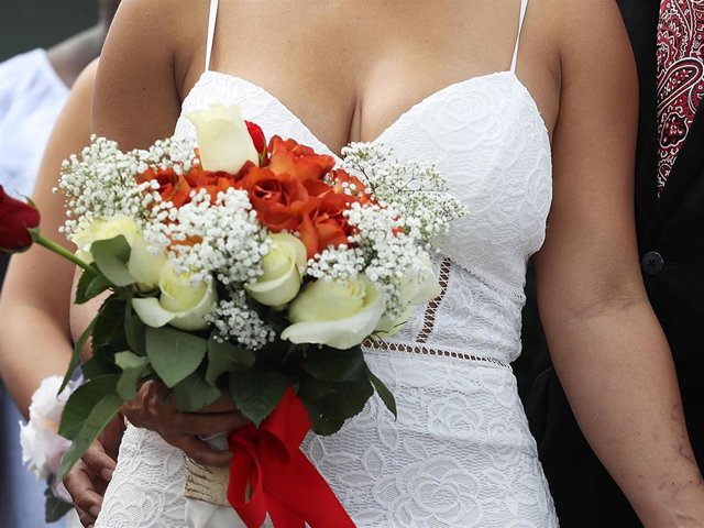 A couple stands together as they participate in a group Valentine's day wedding ceremony at the National Croquet Center on February 14, 2017 in West Palm Beach, Florida.
