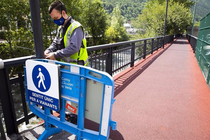 Un operario del Comú de Andorra la Vella reforzando la señalización para establecer un único sentido de circulación para los peatones por el lado del río.