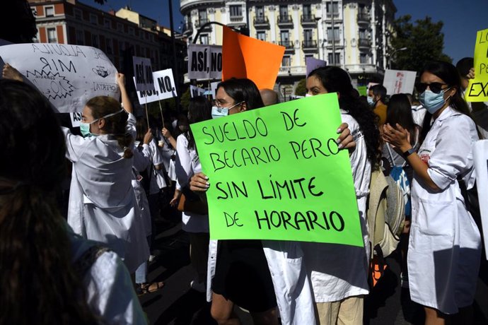 Una sanitaria sostiene un cartel en el que se lee 'Sueldo de becario pero sin límite de horario' durante una manifestación en la que cerca de un millar de médicos internos residentes (MIR) de la Comunidad de Madrid se concentran en su primera jornada de