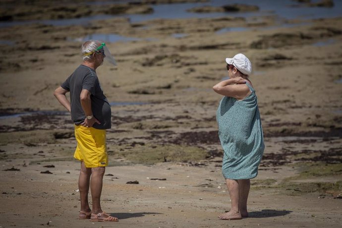 Dos personas conversan a distancia en la playa de La Caleta a 9 de junio de 2020.