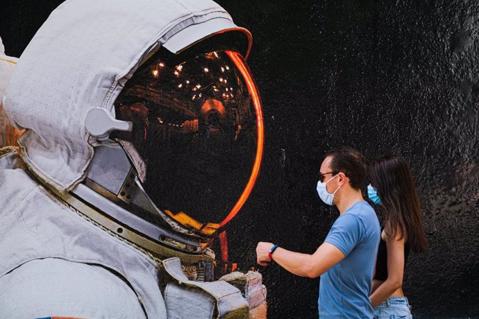 Dues persones amb mscara davant el mural d'un astronauta a Hong Kong
