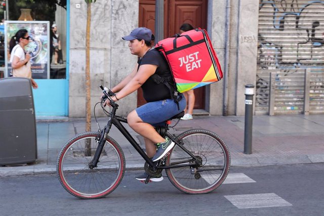 Repartidor de la empresa de reparto Just Eat transitando en bicicleta por una calle del centro de Madrid.