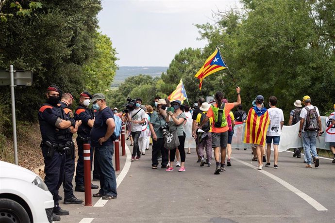 Agentes de los Mossos d'Esquadra observan a los manifestantes que protestan contra la visita del Rey en el Monasterio de Santa Maria de Poblet (Tarragona)