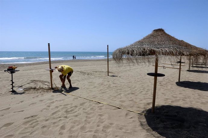 Un trabajador del chiringuito María, ubicado en  la playa de Sacaba en la barriada de Huelín, realiza mediciones de colocación de las sombrillas para  la reapertura 