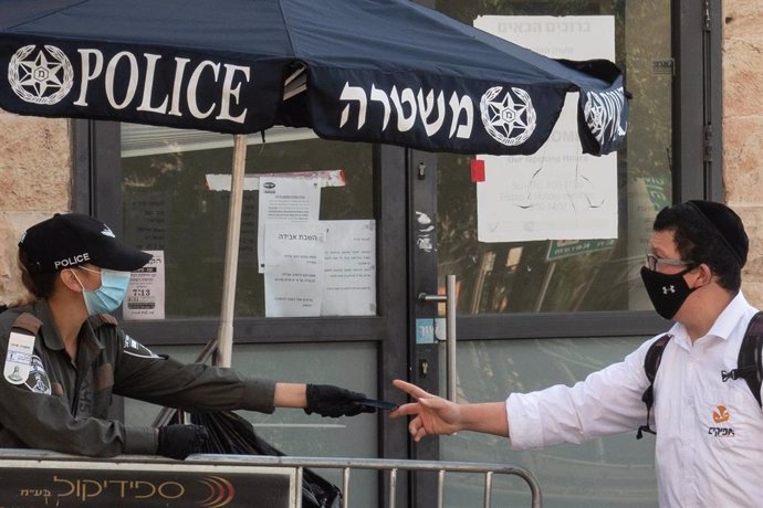 Una policía de Israel habla con un hombre en Jerusalén durante la pandemia de coronavirus 