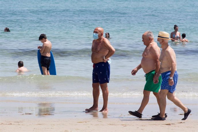 Tres hombres protegidos con mascarillas pasean por la Playa de A Rapadoira en Foz, en la comarca de A Mariña, Lugo, Galicia (España), a 9 de julio de 2020.