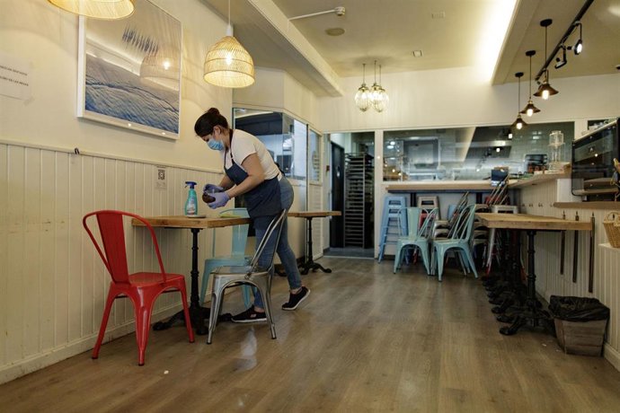 Una camarera limpia una mesa.