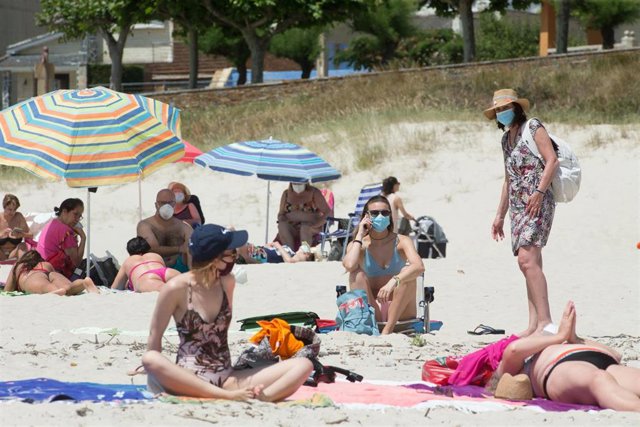 Varias personas protegidas con mascarillas toman el sol en la Playa de A Rapadoira en Foz, en la comarca de A Mariña, Lugo, Galicia (España), a 9 de julio de 2020. El pasado 5 de julio la Xunta ordenó el cierre hasta mañana 10 de julio de los accesos del 