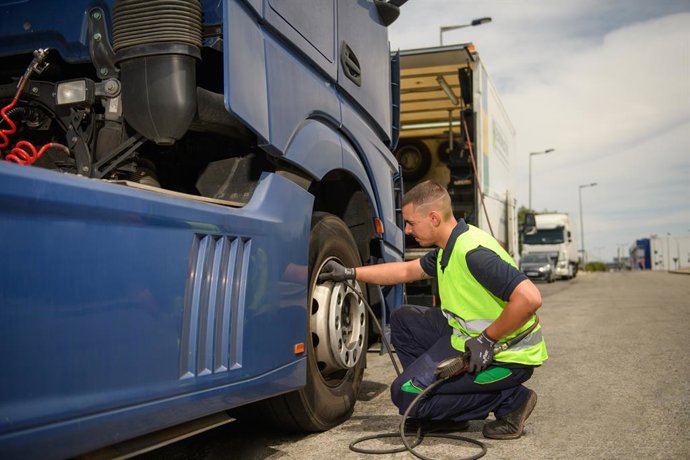 Imagen de un camionero comprobando sus neumáticos.