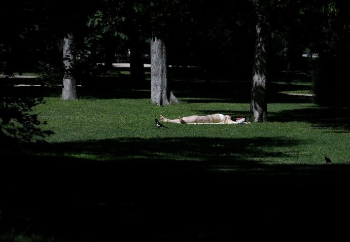 Una joven toma el sol en el césped en el Parque del Retiro en Madrid (España), a 29 de junio de 2020. 