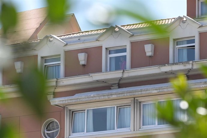 Una persona mira por una ventana del hotel NH Finisterre de A Coruña donde los jugadores del CF Fuenlabrada permanecen confinados en él tras haber dado positivo en coronavirus varios de sus miembros