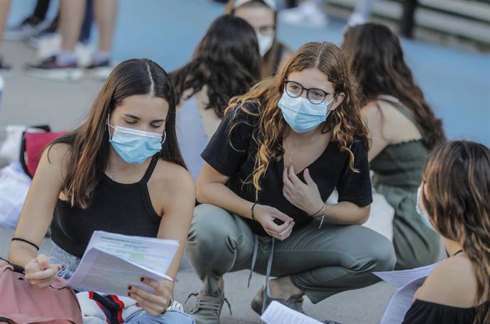Estudiantes de bachillerato sentados en las instalaciones exteriores minutos antes de entrar a las aulas para realizar los exámenes Selectividad o Pruebas de Acceso a la Universidad.