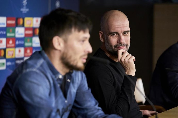 25 February 2020, Spain, Madrid: Manchester City's David Silva (L) and manager Pep Guardiola attend a press conference ahead of Wednesday's UEFAChampions League round of 16 first leg soccer match against Real Madrid