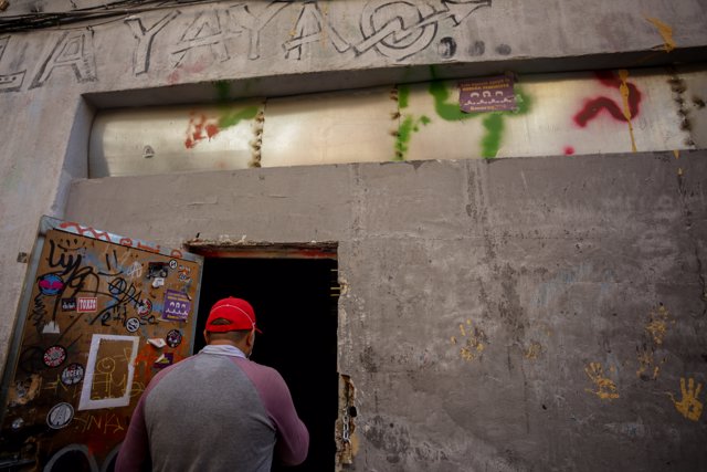 Una persona entra por la puerta del local okupado por el colectivo 'La Yaya' en Madrid