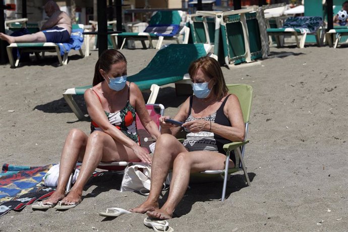 Dos mujeres con mascarillas en la playa 