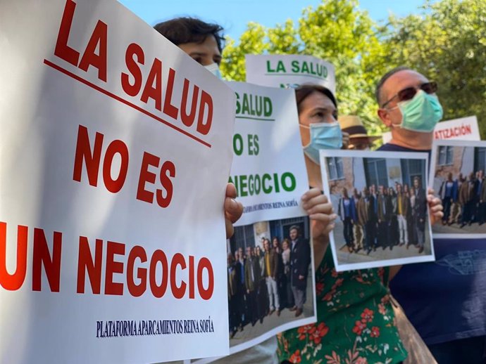 Integrantes de Aparcamientos Reina Sofía, en una concentración, muestran fotos con dirigentes del PP que pedían la gratuidad del parking que ahora niegan.